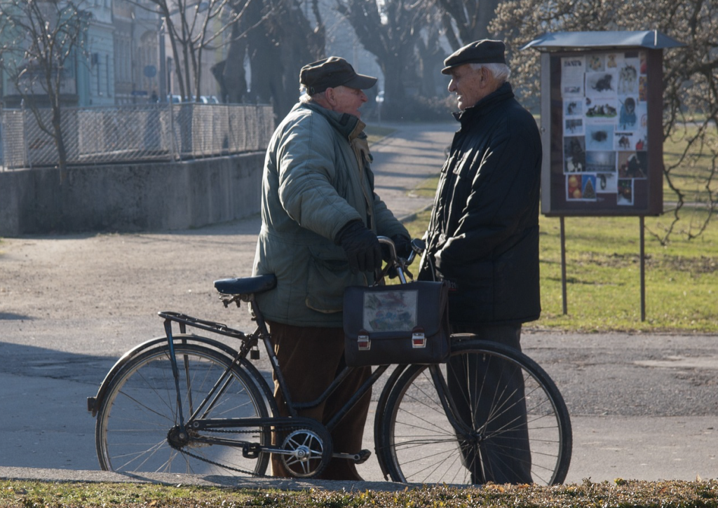 two men standing and talking with bike