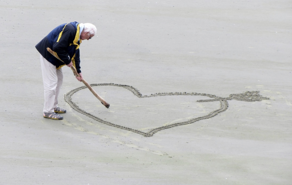 man drawing a heart in the sand
