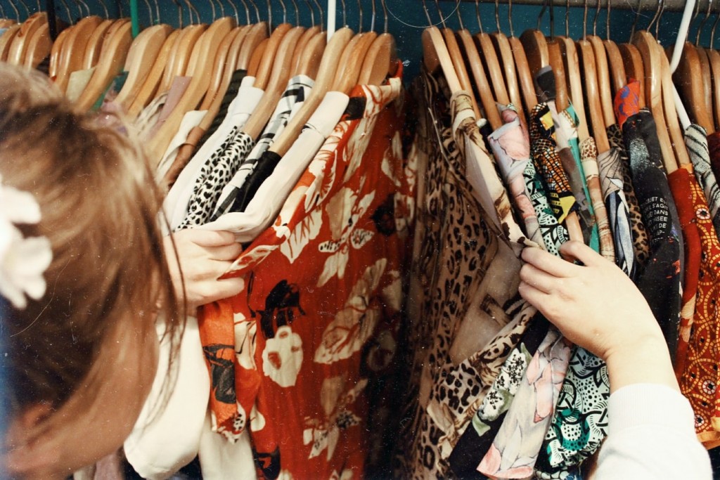 A girl looking through a rail of shirts in a shop.